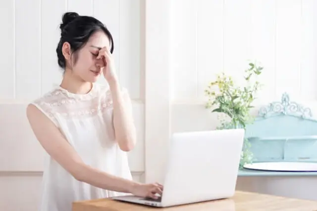 スマホやパソコンを使い過ぎて、頭が痛い症状が出ている女性